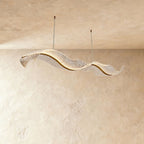 This Clérachic ribbon chandelier curls into a flowing double wave, its surface catching warm ambient light.