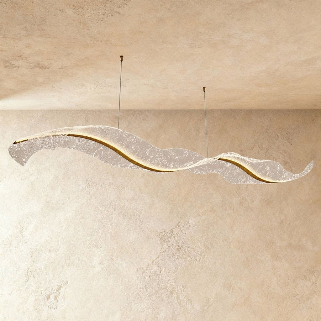 Clérachic's sculptural wave chandelier stretches long and low, its textured surface glowing softly.
