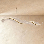 Clérachic's sculptural wave chandelier stretches long and low, its textured surface glowing softly.