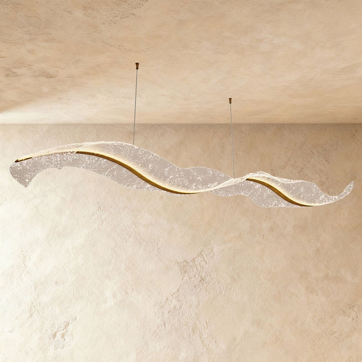 Clérachic's sculptural wave chandelier stretches long and low, its textured surface glowing softly.
