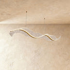 This Clérachic ribbon-form chandelier sweeps into a long wave, its textured surface softly backlit.
