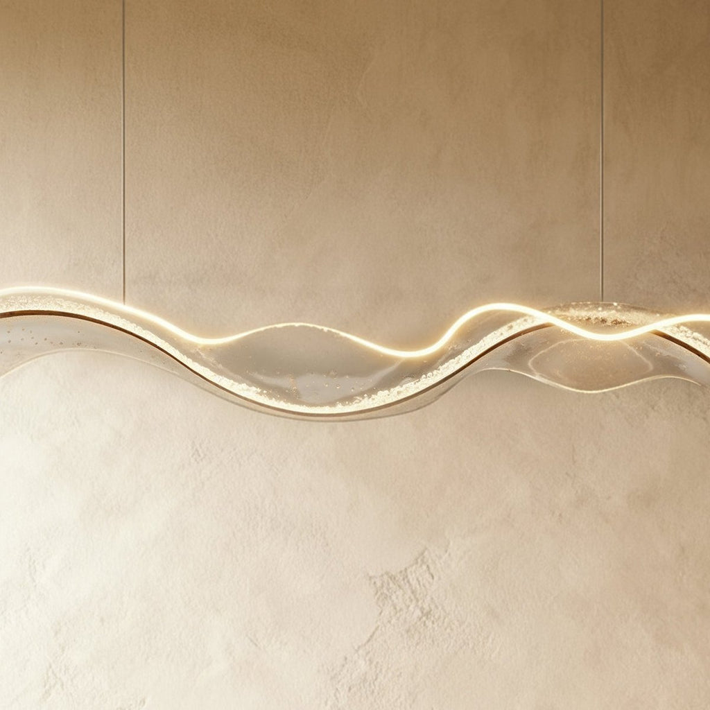 Close-up of the lit Clérachic chandelier shows a dimpled, water-ripple texture along its LED edge.