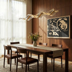 A lit Clérachic wave chandelier curves above a walnut dining table beneath a bold graphic artwork.