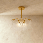 Clérachic Isla chandelier in frosted translucent glass, disc petals fanned from a brass stem against a plaster ceiling.