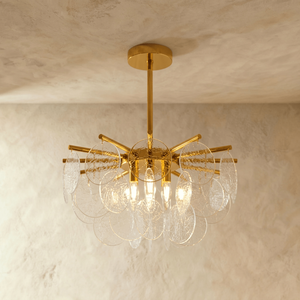 Clérachic Isla chandelier in clear transparent glass, textured discs radiating from a brass stem, lit warm within.
