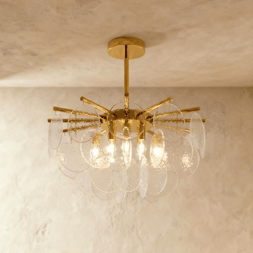 Clérachic Isla chandelier lit warm in clear transparent glass, hammered-texture discs fanned from a brass frame.