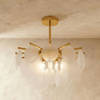 Clérachic Isla chandelier lit warm, frosted translucent glass petals clustered densely around a brass ceiling stem.