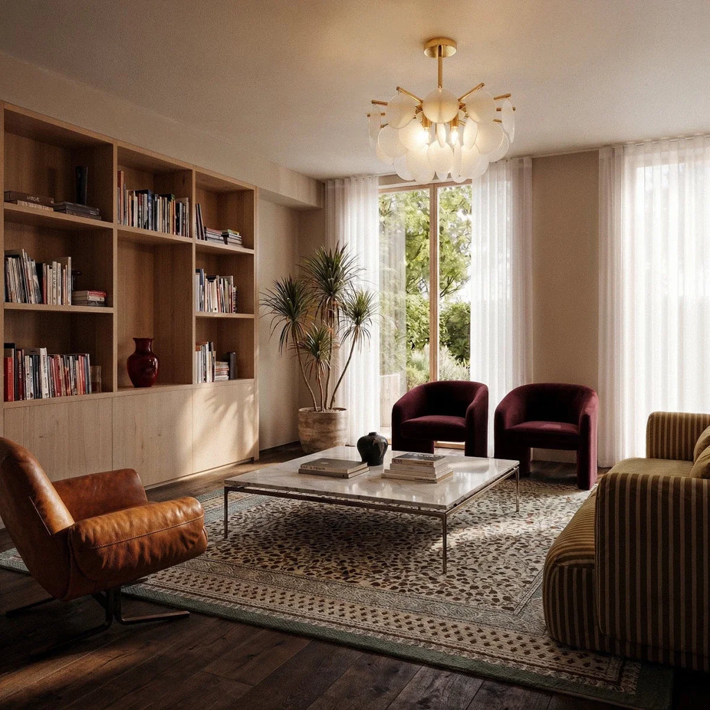 Clérachic Isla chandelier in translucent glass lit warm above a living room with bookshelves and burgundy chairs.