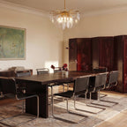 Clérachic Isla chandelier in transparent glass lit warm above a dark wood dining table set for eight guests.