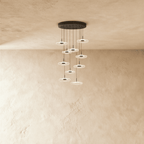 Clérachic staircase chandelier in black, a tall spiral of glowing flower-shaped discs cascading from the ceiling.