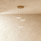 Clérachic staircase chandelier in gold, three flower-shaped LED discs cascading on cables from a round ceiling plate.