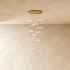 Clérachic staircase chandelier in gold, a tall spiral of glowing flower-shaped discs cascading from the ceiling.