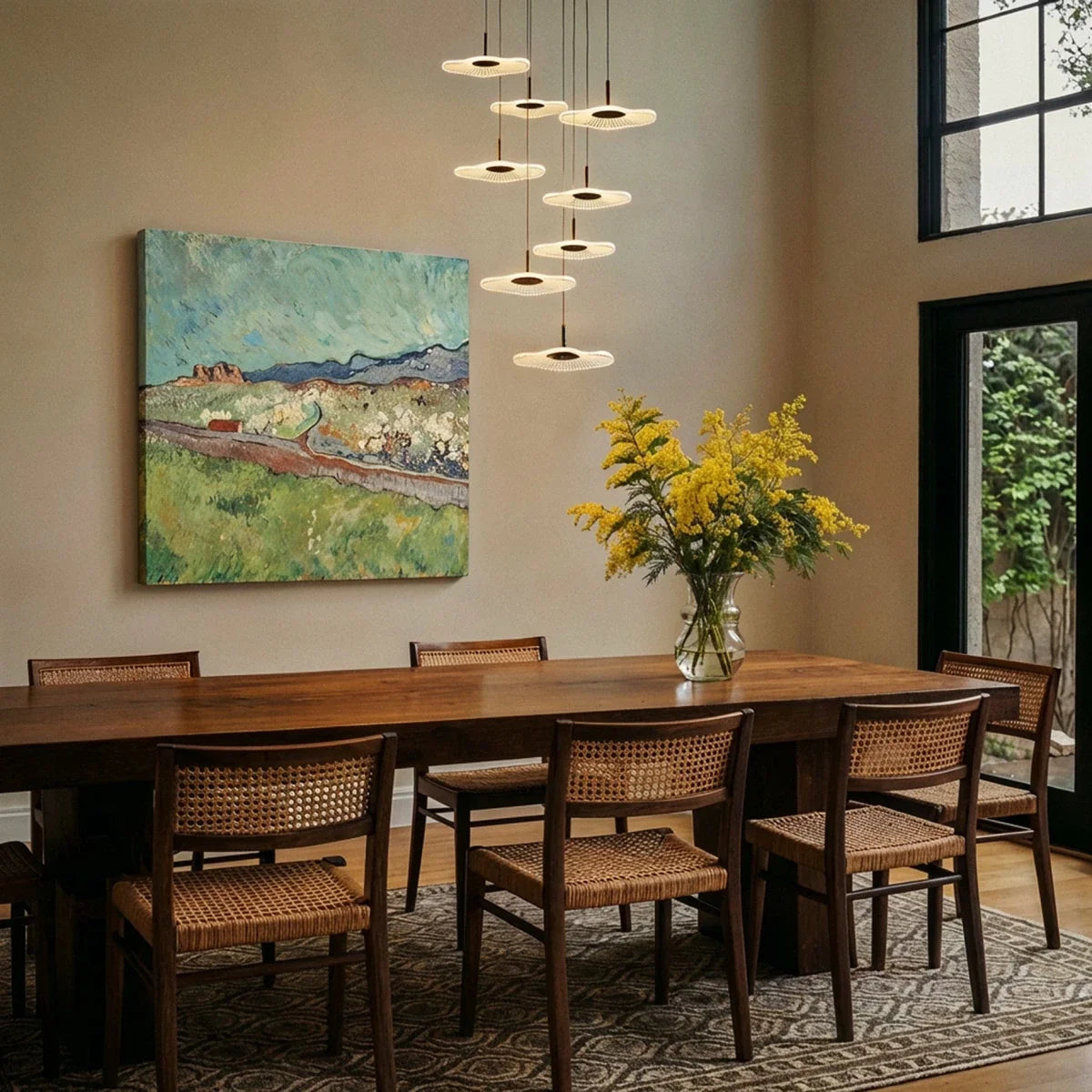 Clérachic staircase chandelier in black suspended over a dining table, its glowing discs staggered above cane chairs.