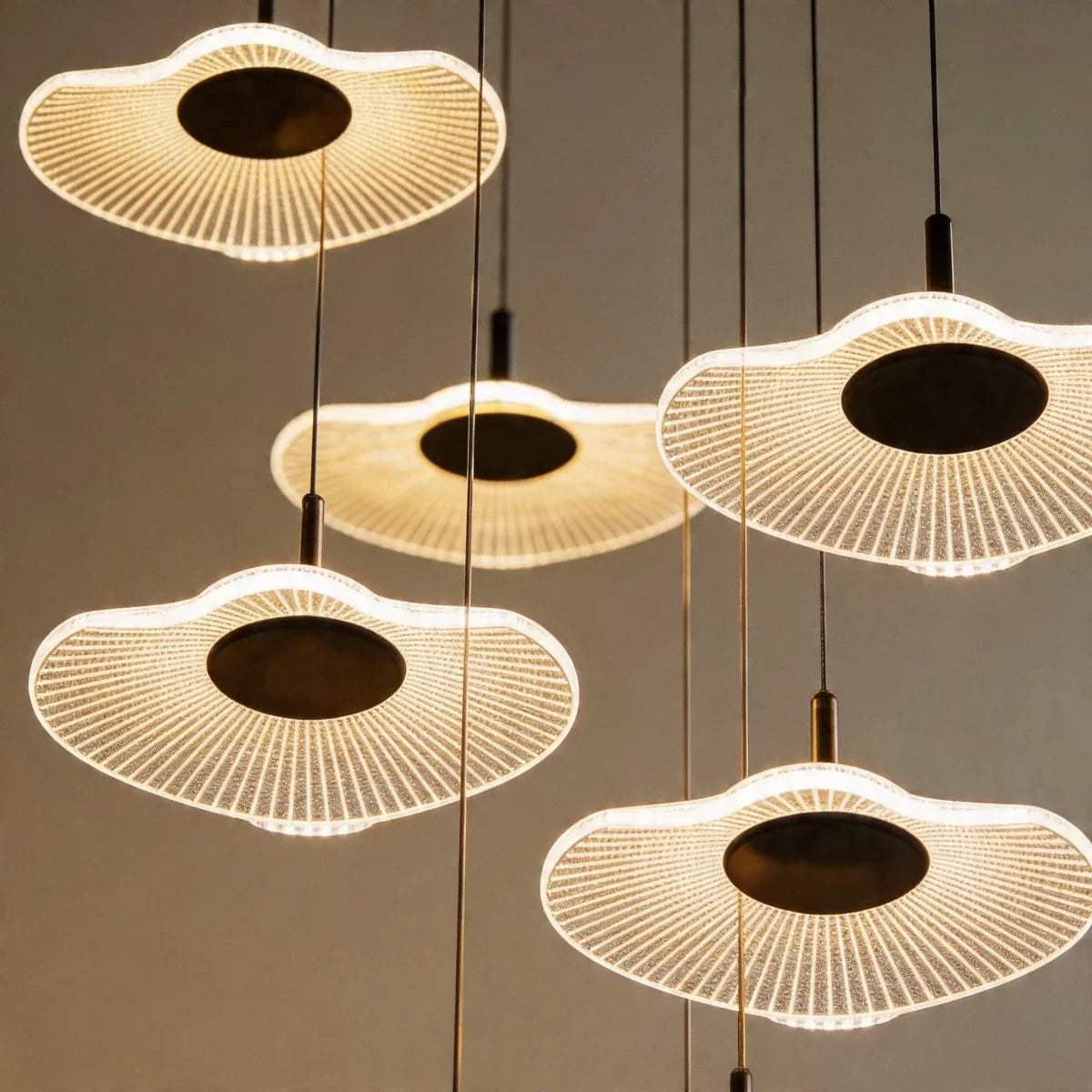 Close-up of the Clérachic staircase chandelier's ribbed flower-shaped discs, each glowing warm white at its centre.