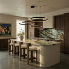 A matte black Clérachic three-ring chandelier lights a marble kitchen island beneath dark wood cabinetry.