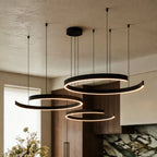 This matte black Clérachic three-ring chandelier casts warm light over a marble island and green backsplash.