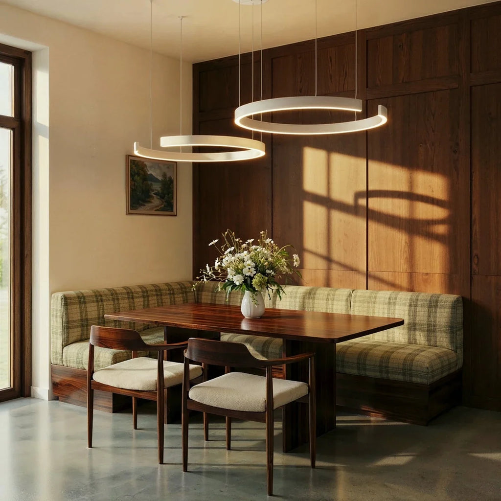 A matte white Clérachic two-ring chandelier hangs over a plaid banquette in a wood-paneled dining nook.