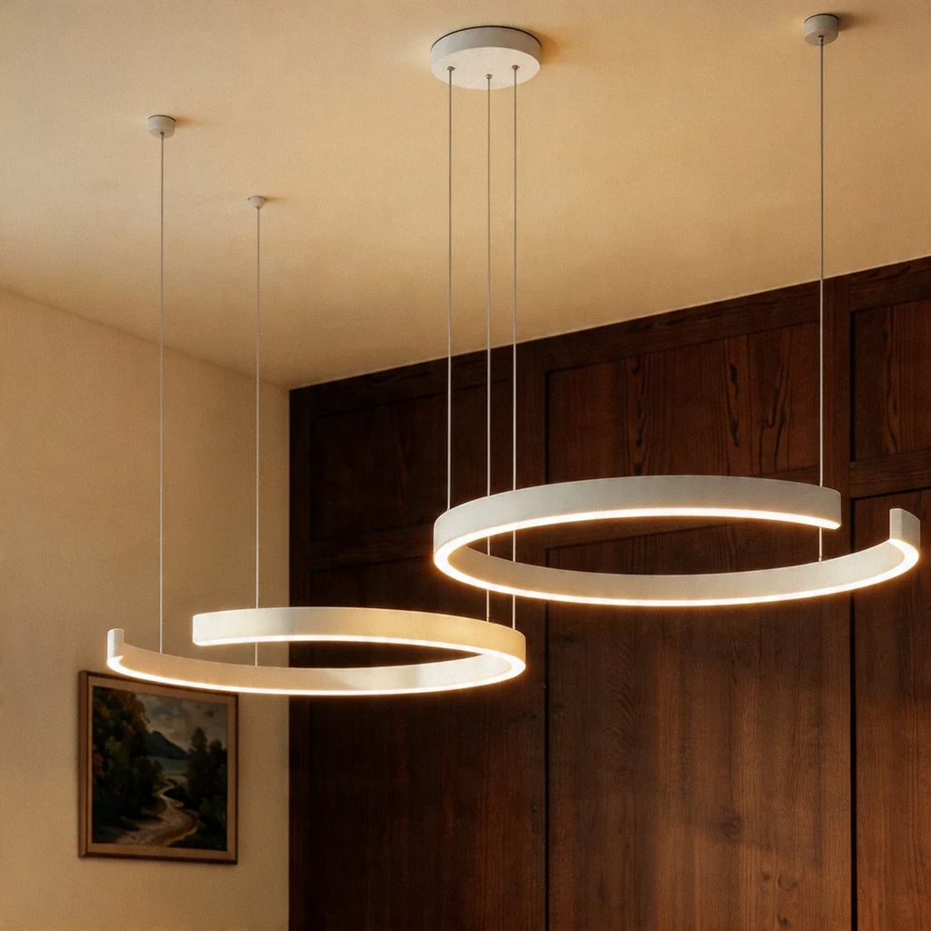 A matte white Clérachic two-ring chandelier lights a dining nook beside a framed landscape painting.