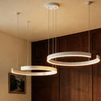 A matte white Clérachic two-ring chandelier lights a dining nook beside a framed landscape painting.