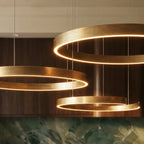 A close view shows the Clérachic chandelier's brushed gold rings glowing warmly above a green marble counter.