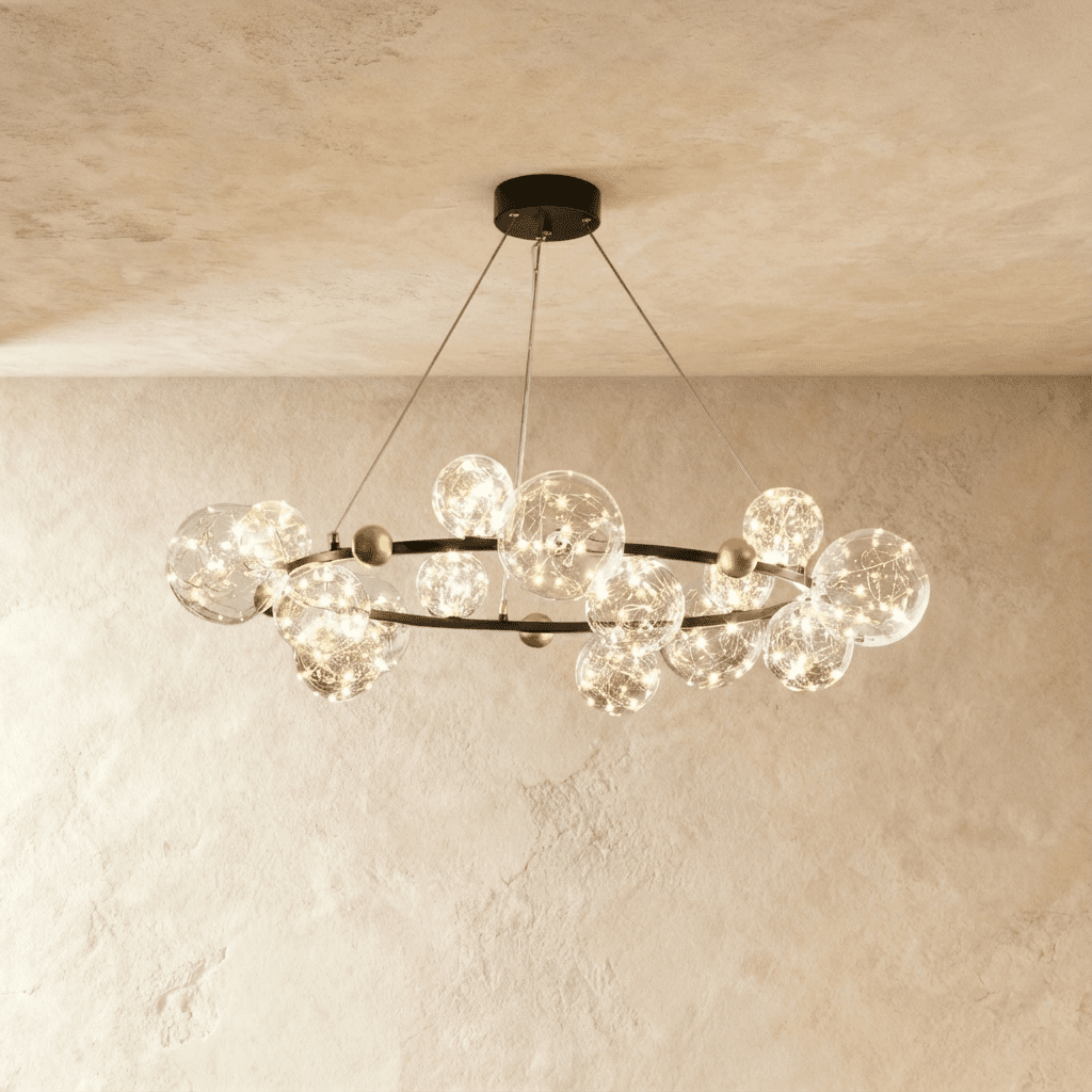 Clérachic chandelier in black, clear glass globes with warm fairy-light filaments ringing a round brass-dotted frame.