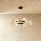 Clérachic chandelier in black with fewer glass globes clustered around the round frame, glowing warm white.