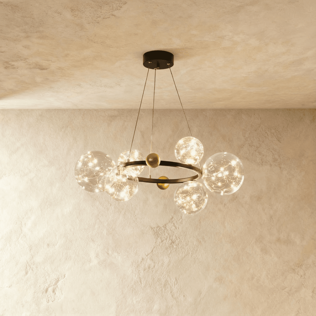 Clérachic chandelier in black with fewer glass globes clustered around the round frame, glowing warm white.