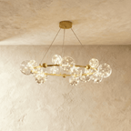 Clérachic chandelier in gold, clear glass globes with warm fairy-light filaments ringing a round brass frame.