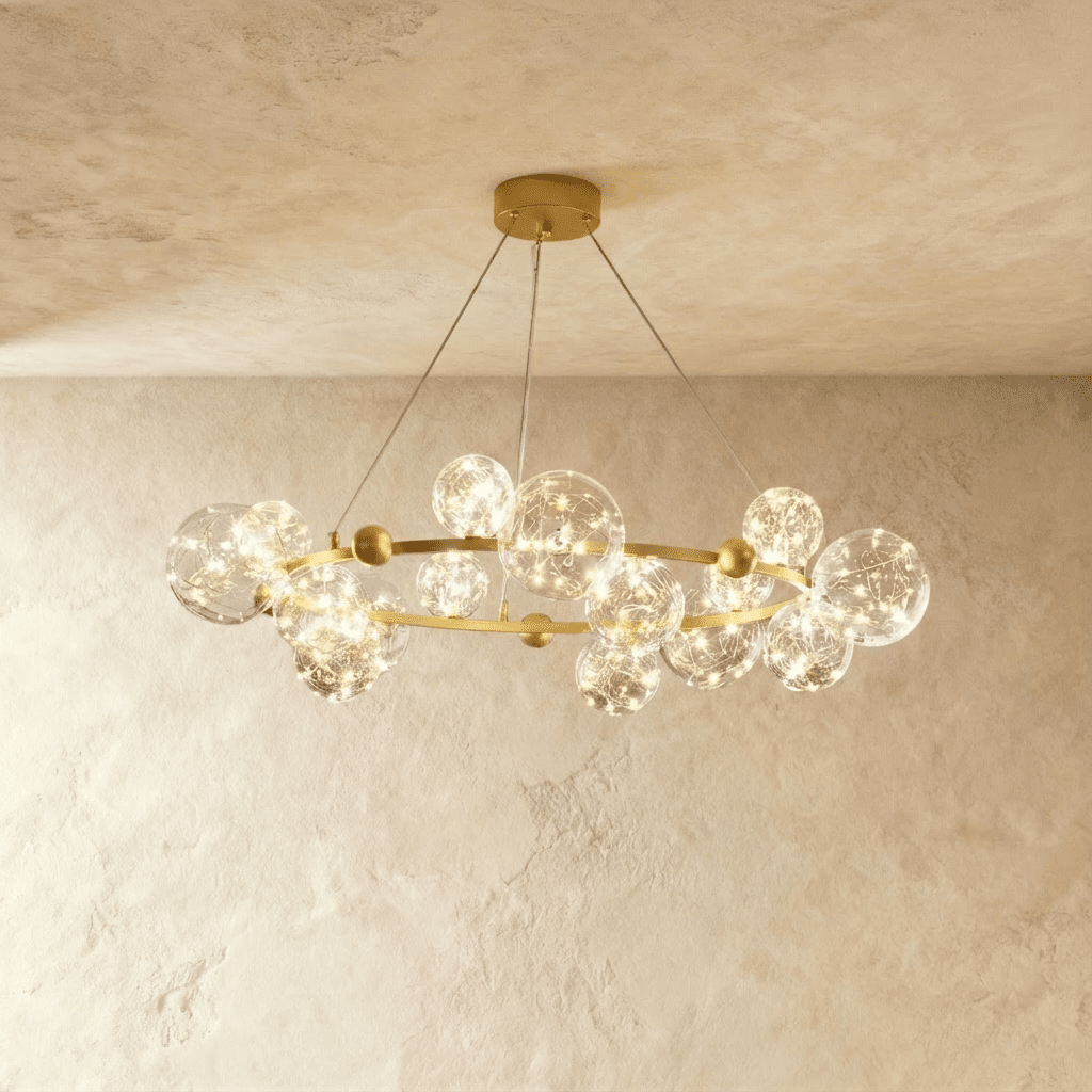 Clérachic chandelier in gold, clear glass globes with warm fairy-light filaments ringing a round brass frame.