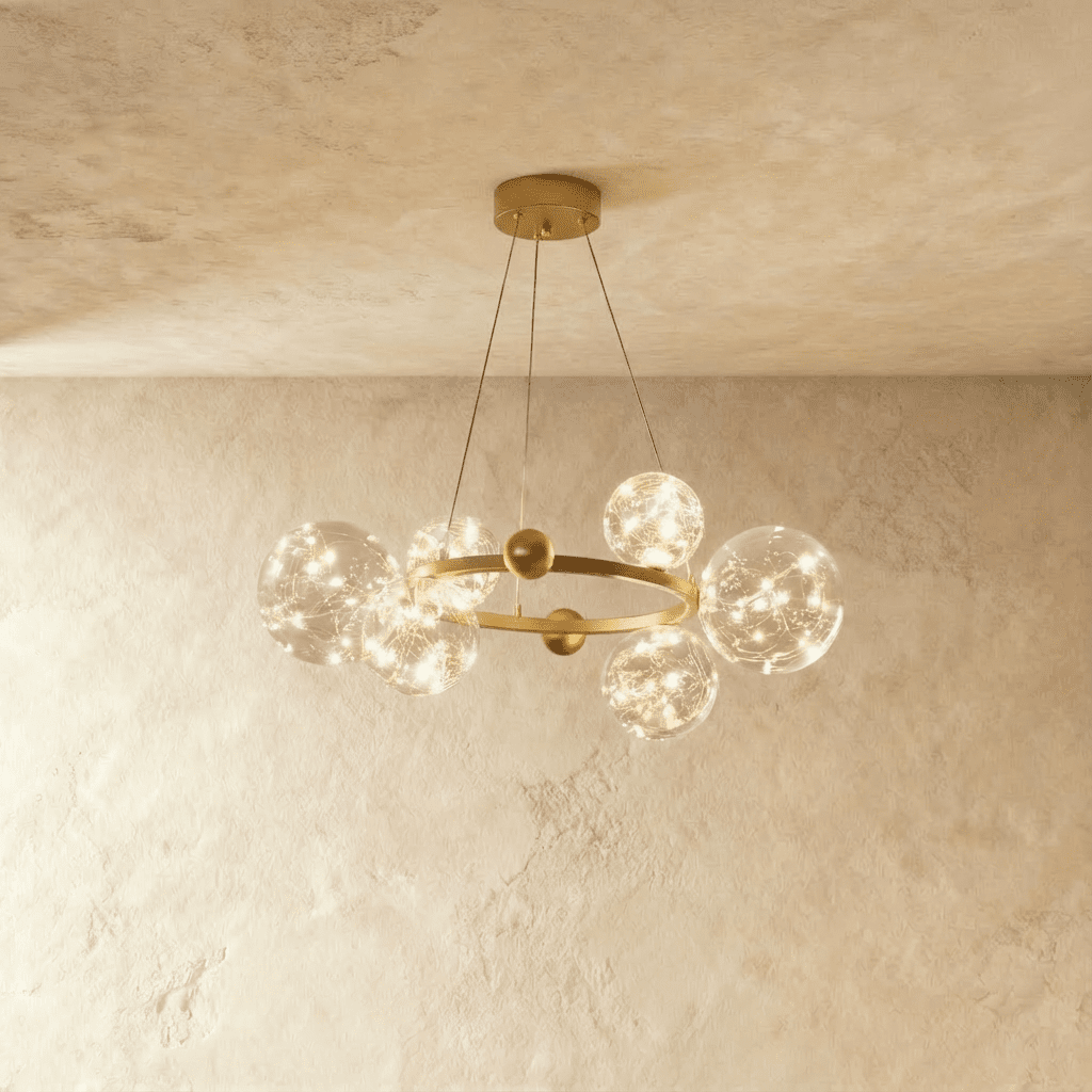 Clérachic chandelier in gold with fewer glass globes clustered around the round frame, glowing warm white.