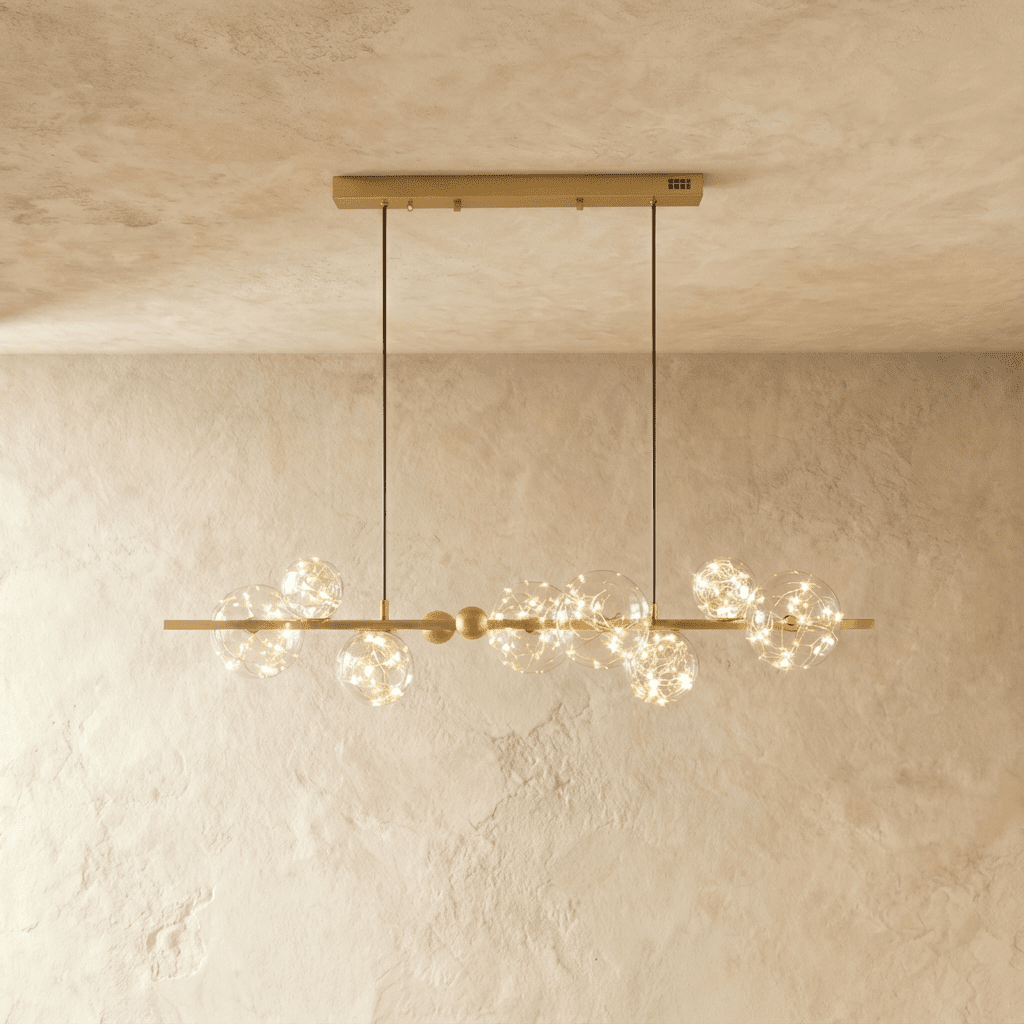 Clérachic chandelier in gold, a linear brass bar strung with glowing glass bubble globes along its length.