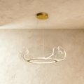 Clérachic gold-finished chandelier with a ring of clear acrylic leaf shades, hung from a round canopy against limewash.