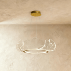 Clérachic gold-finished chandelier with a ring of clear acrylic leaf shades, hung from a round canopy against limewash.