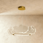 Clérachic leaf chandelier with veined clear acrylic petals around a gold ring, lit softly and hung from three fine cables.