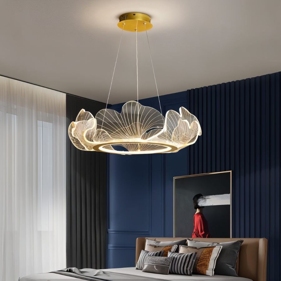 Clérachic leaf chandelier in clear acrylic and gold above a bed, set against navy panelling and sheer curtains.