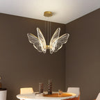 Clérachic gold butterfly chandelier with four clear acrylic wing pairs, over a marble-topped dining table in a taupe room.