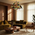 Clérachic twelve-parrot stained-glass style chandelier over a low wooden coffee table and an olive velvet sofa.