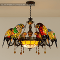 Clérachic chandelier of six glass parrots on dark arms, a pale amber glass bowl and amber crystal drops, on a chain.