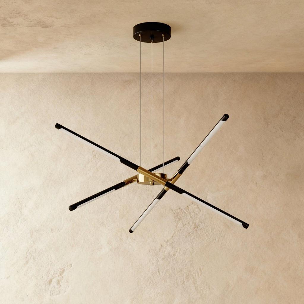 Clérachic starburst chandelier with six slim LED rods in black and brushed gold, hung on three cables against plaster.