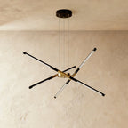 Clérachic starburst chandelier with six slim LED rods in black and brushed gold, hung on three cables against plaster.