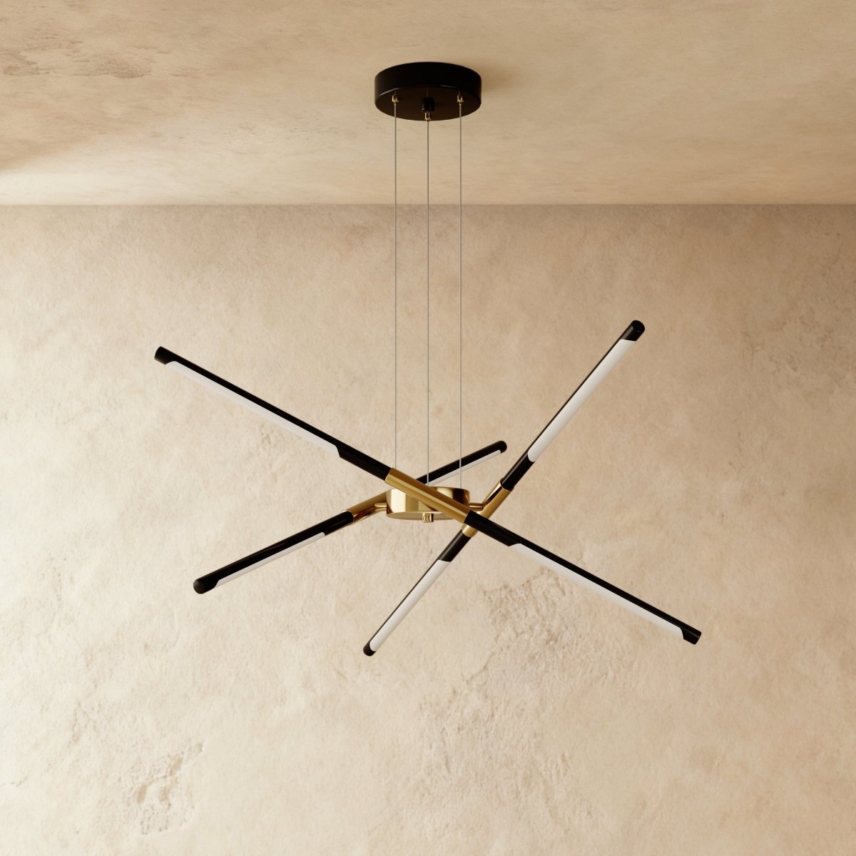 Clérachic starburst chandelier with six slim LED rods in black and brushed gold, hung on three cables against plaster.