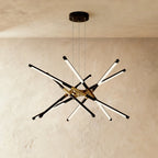 Clérachic twelve-rod starburst chandelier in black and gold, a dense burst of slim LED rods on three suspension cables.