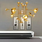Gold trumpet-head Clérachic chandelier hung above a low grey sofa, with a triptych of ship prints on the wall behind.