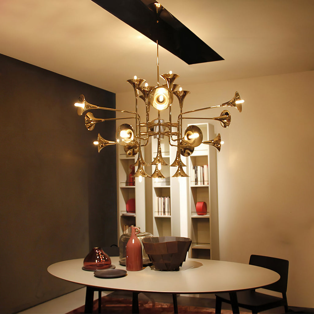 Warmly lit Clérachic chandelier with gold horn shades over a round dining table, with open shelving and ceramics behind.
