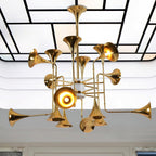 Looking up at the gold horn-shaped heads of this Clérachic chandelier, set against a ceiling of white panels and black lines.