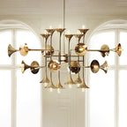 Gold Clérachic chandelier with horn-shaped shades, hung in front of two tall arched windows with white framing.