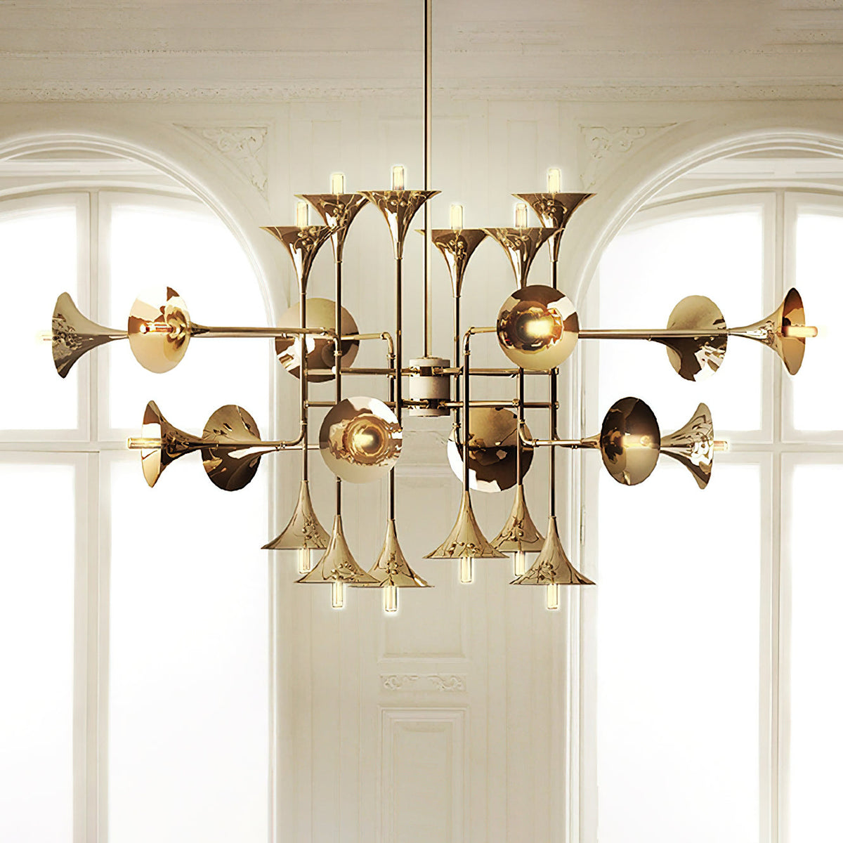 Gold Clérachic chandelier with horn-shaped shades, hung in front of two tall arched windows with white framing.