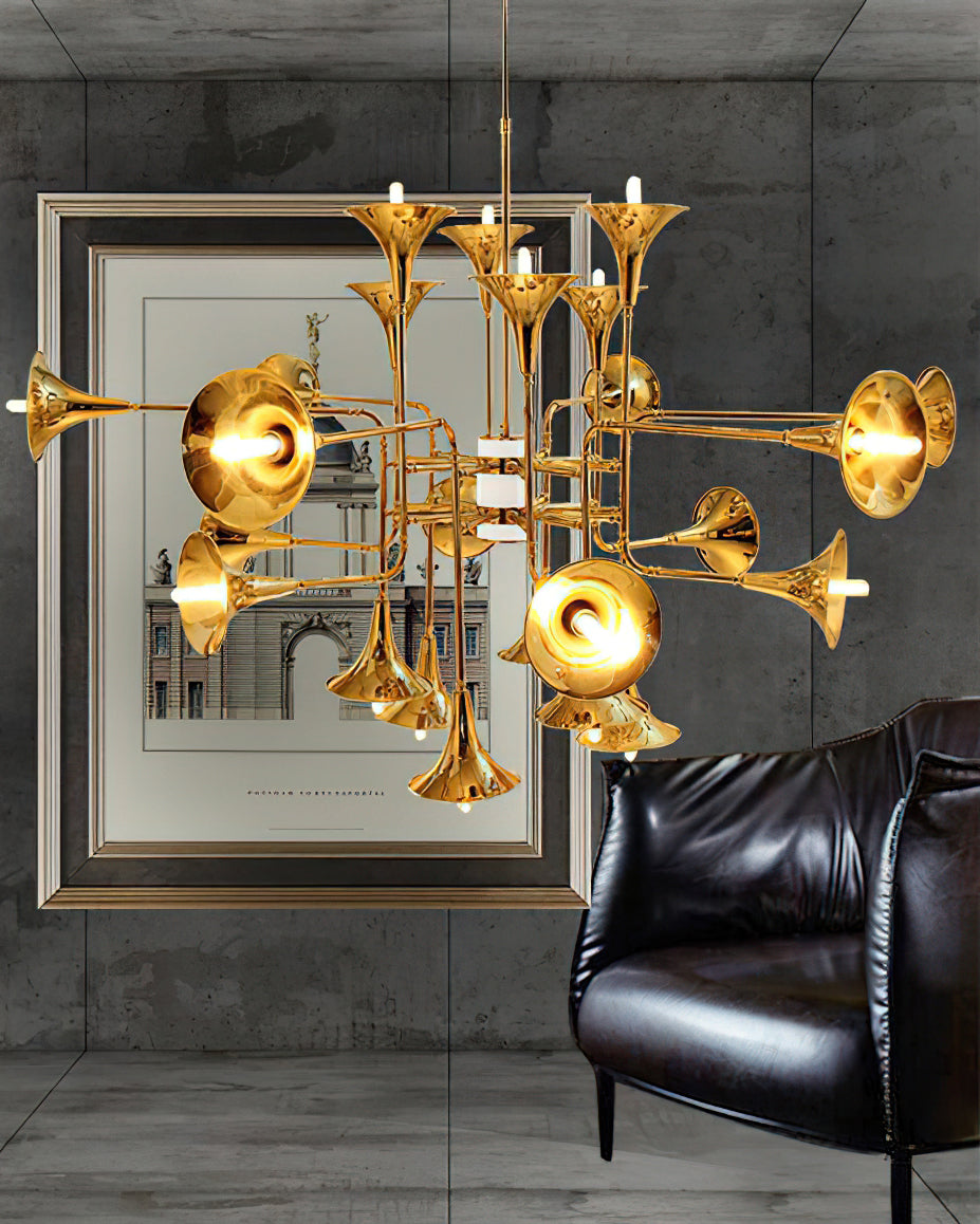 Gold trumpet-head Clérachic chandelier in a grey concrete-walled room, beside a framed print and a black leather armchair.