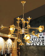 Gold Clérachic chandelier lit above a rough stone wall and a wooden counter, in a restaurant-style setting.