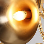 Close view of a gold horn on this Clérachic chandelier, its polished inner surface glowing around a candle-style bulb.